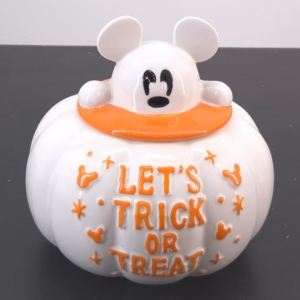 Close-up of a white cartoon bear figure wearing an orange scarf, with orange raised letters across its belly.