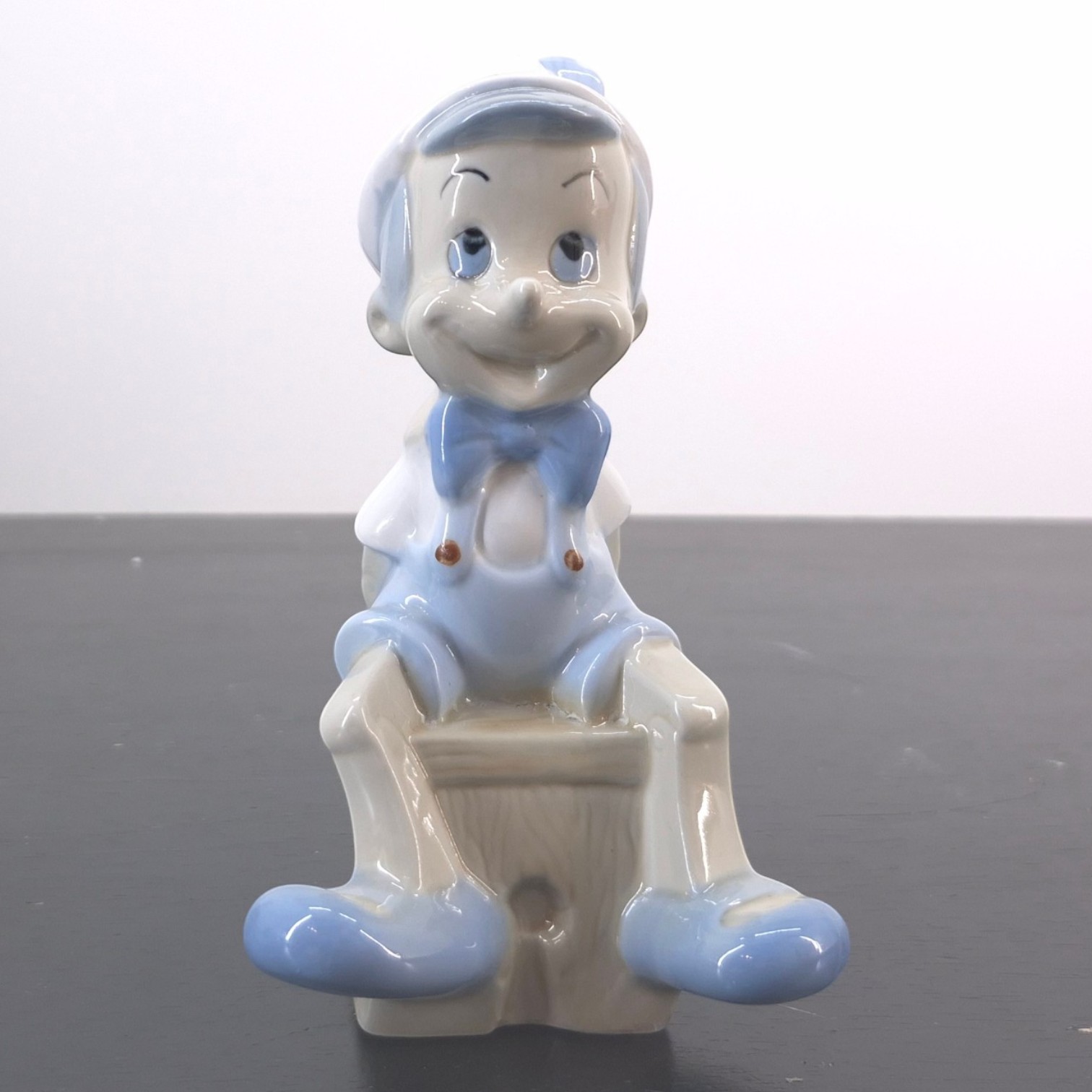Vintage Pinocchio Figurine - Pinocchio figurine seated on small block in blue outfit